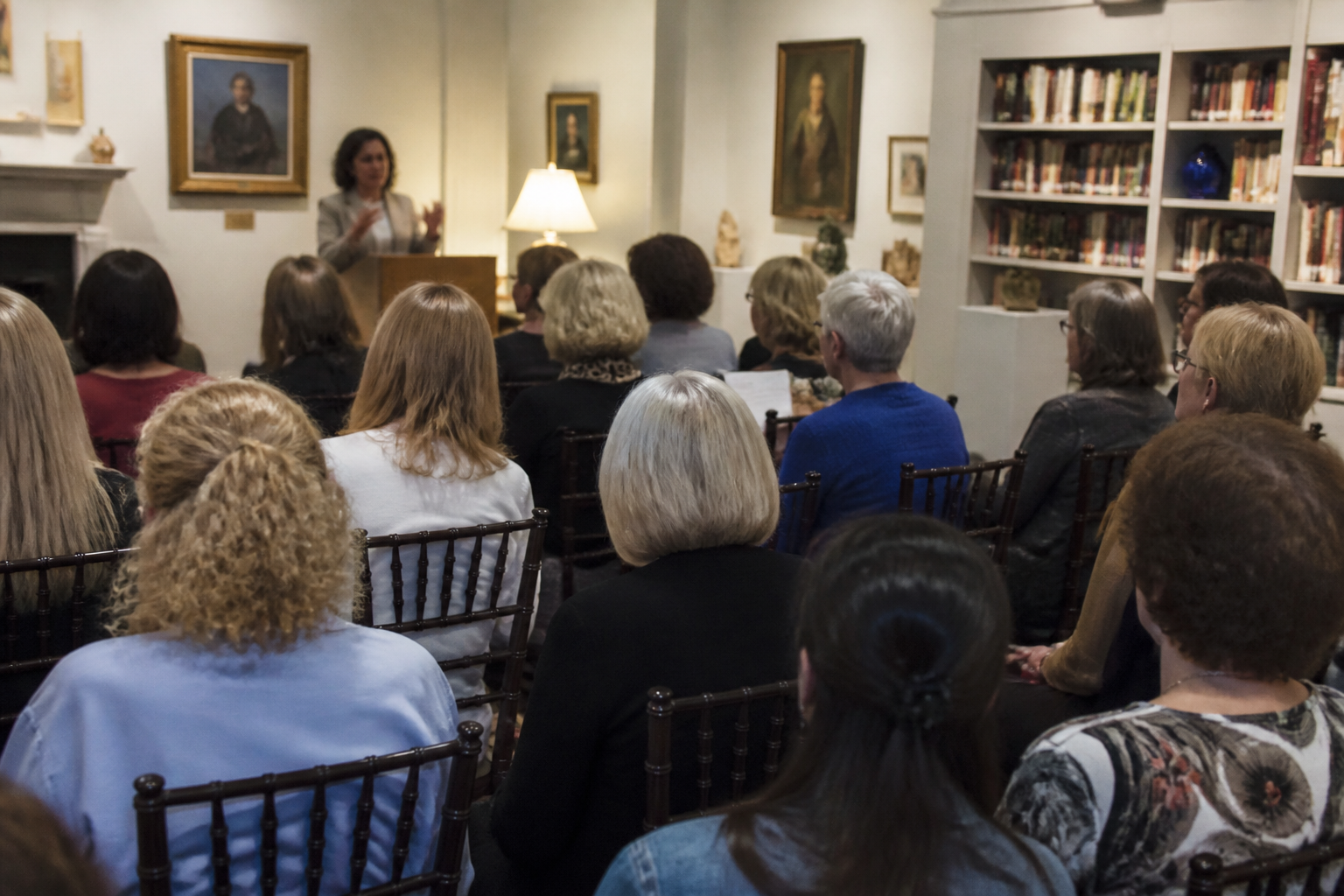 Adults attend a Sunday lecture at The Women’s Institute of Houston with books and local art visible.