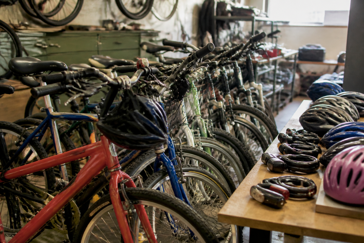 Refurbished bicycles with helmets, locks, and lights are staged inside Community Bicycle Shop for redistribution.