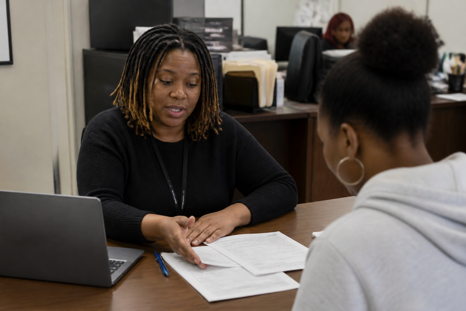 DEAC staff points a tenant to application links and printed court forms at an intake desk in Dallas.